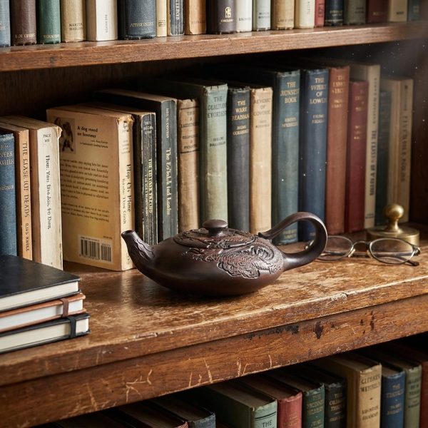 Théière en poterie du Yunnan 170 ml — dragon en relief, sur une étagère de bibliothèque