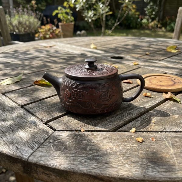 Théière en poterie pourpre 200 ml — forme tuile Han, phénix, sur une table de jardin en teck