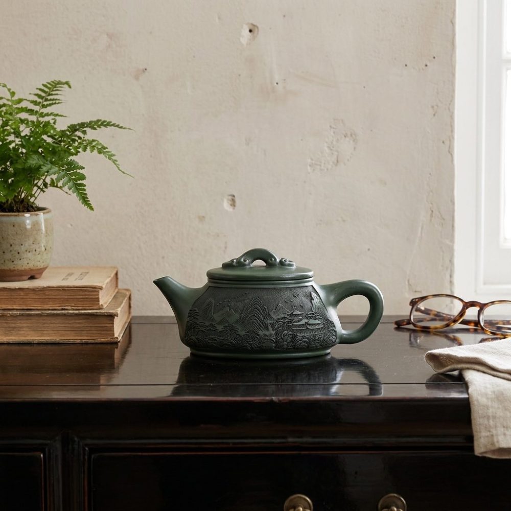 Théière de Yixing 340 ml — paysage gravé, argile verte, sur une console laquée