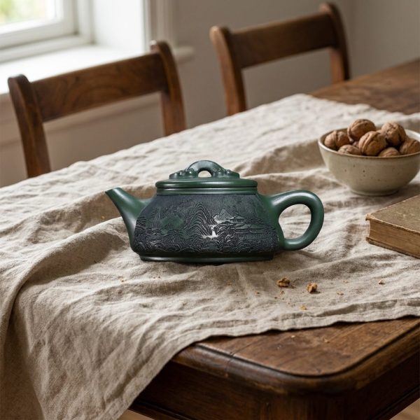 Théière de Yixing 340 ml — paysage gravé, argile verte, sur une table de salle à manger en noyer