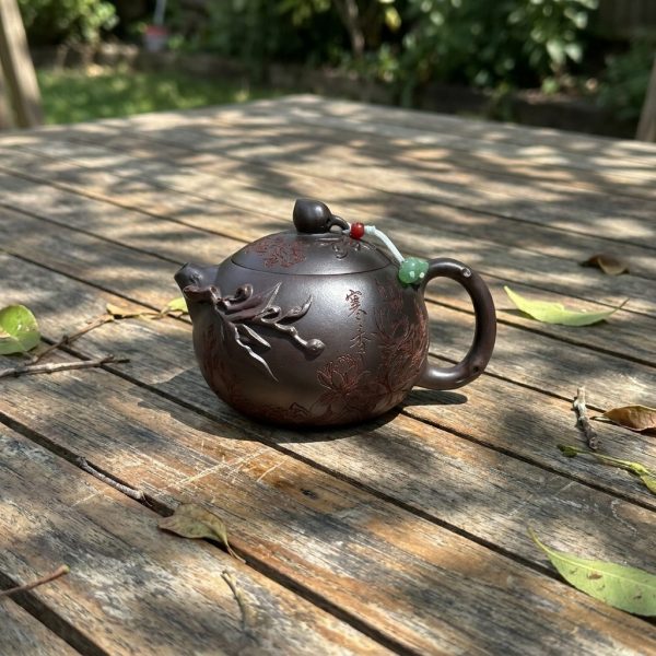 Théière de Yixing 280 ml — pêche sculptée, sur une table de jardin en teck