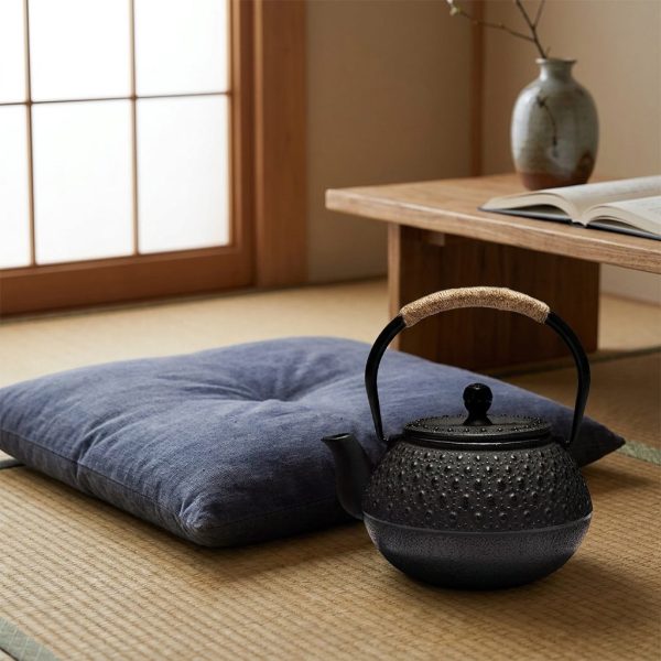 Théière en fonte 900 ml à picots arare noirs, sur un tatami, à côté d’un coussin