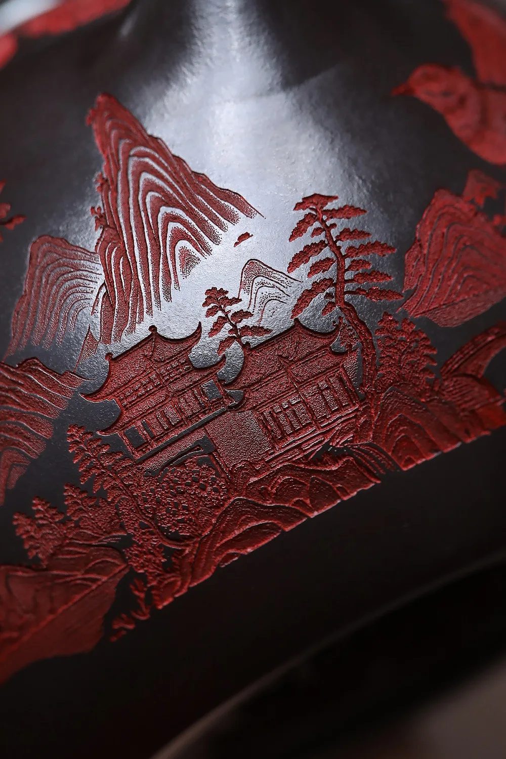 Détail du décor sculpté : montagne, pagode et pins gravés en rouge dans l'argile