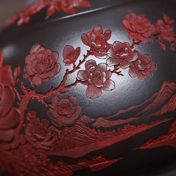 Détail du décor sculpté : branche de pivoines en relief rouge sur l'argile noire