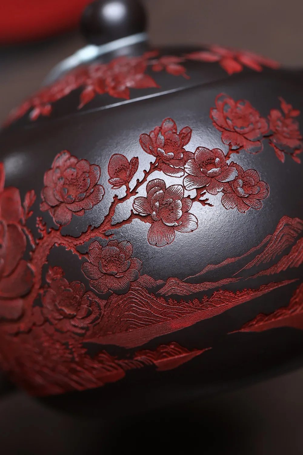 Détail du décor sculpté : branche de pivoines en relief rouge sur l'argile noire